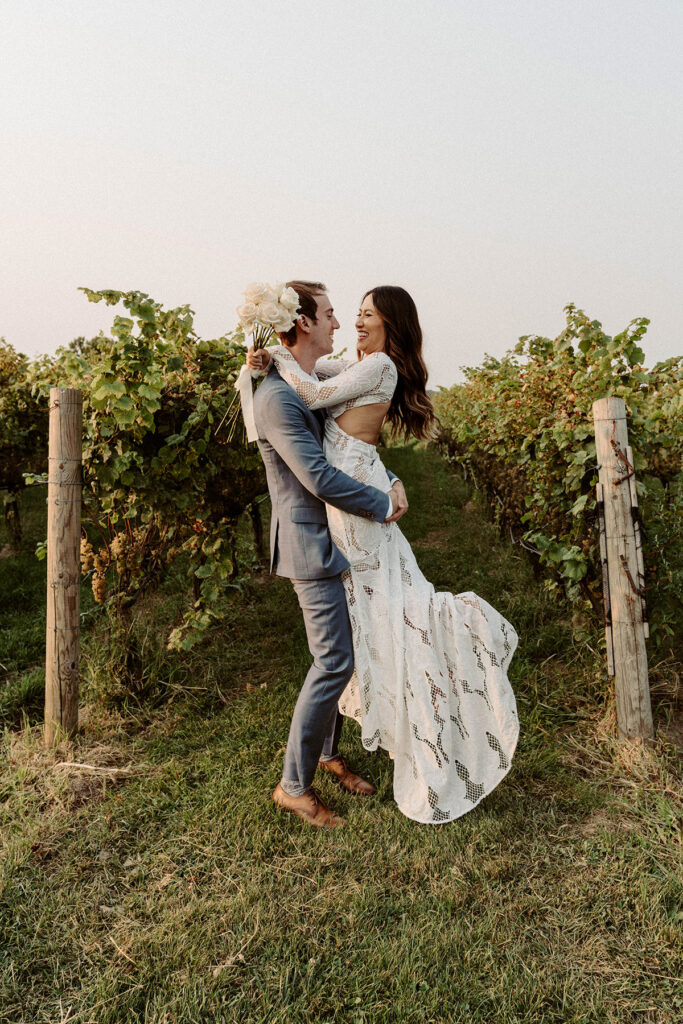 A man lifting up his bride in a vineyard