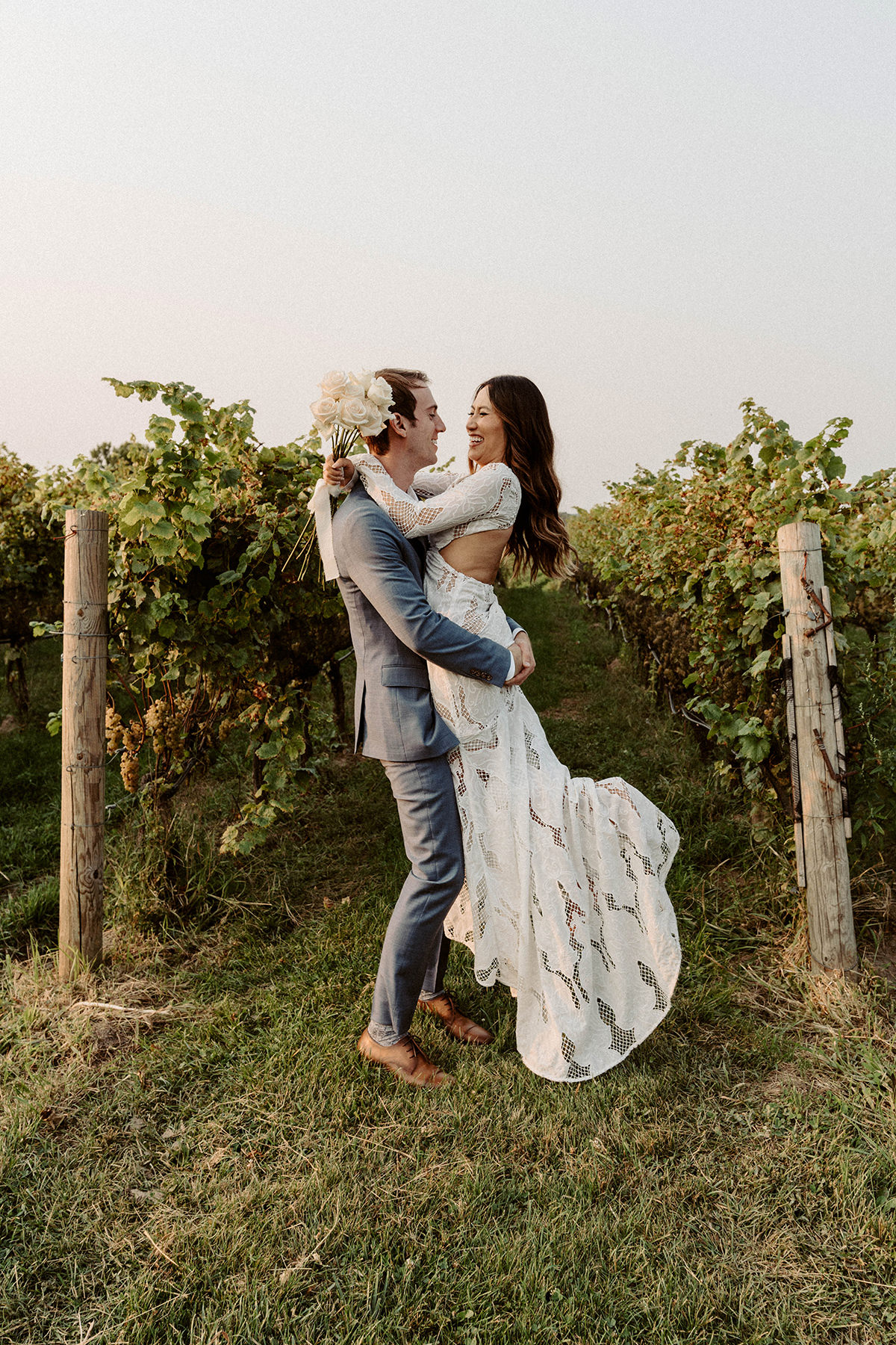 A man lifting up his bride in a vineyard