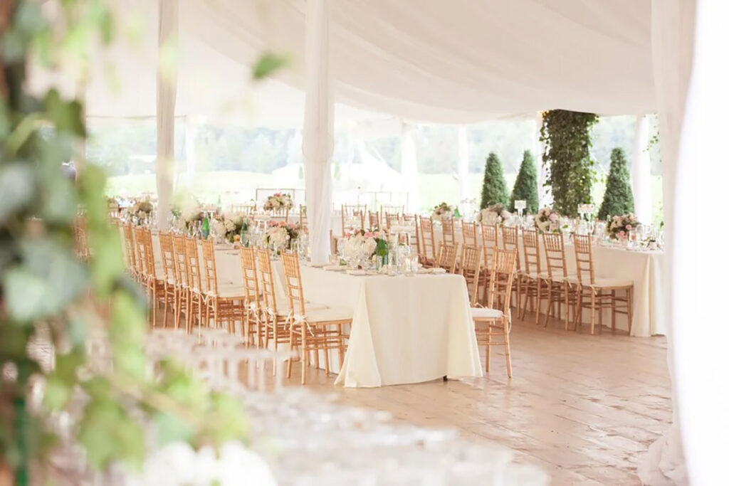 Reception tables set up under a tent with gold chivari chairs