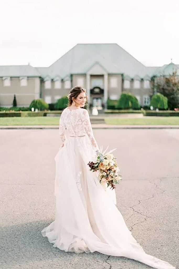 A bride walking away looking back with flowers in hand