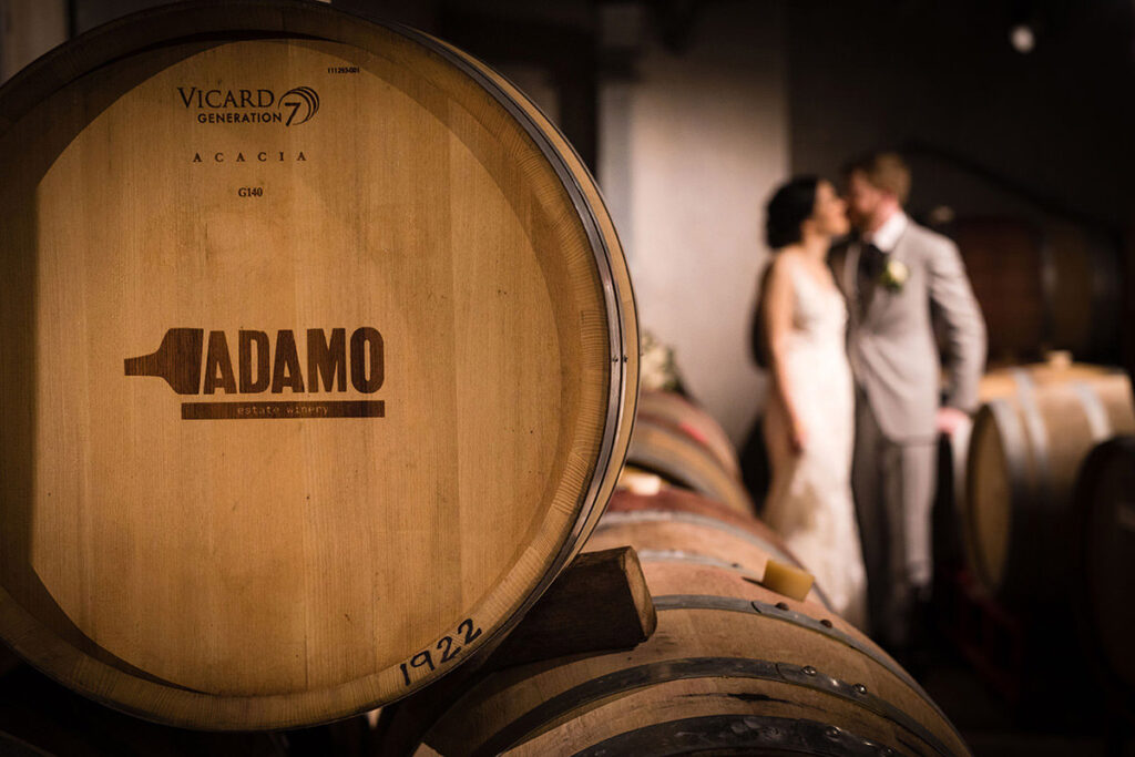A branded wine barrel with a bride and groom kissing in the back
