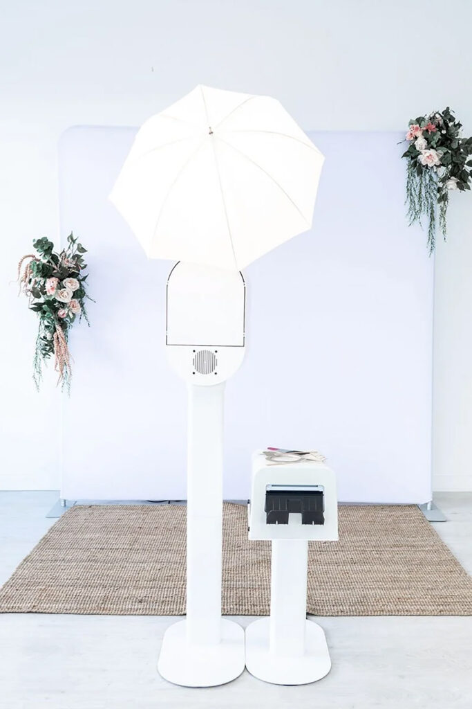 A self serve photo booth set up with a white backdrop