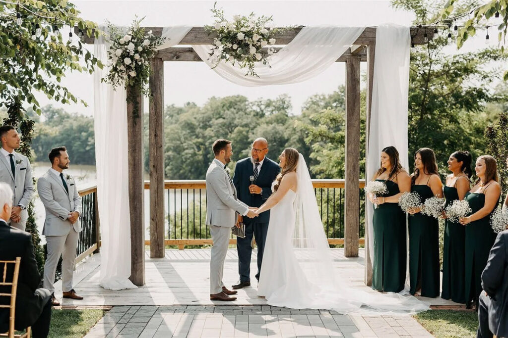 A ceremony under an arbour with delicate white draping