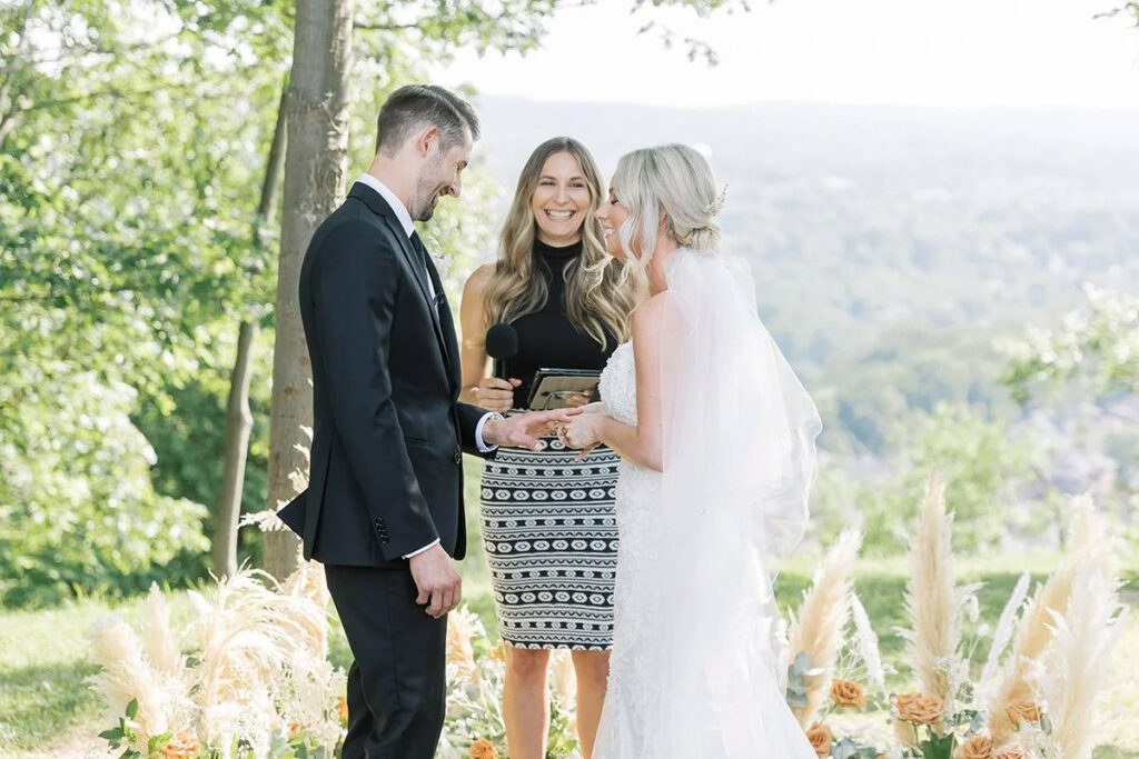 A bride and groom at their ceremony with a vineyard in the back