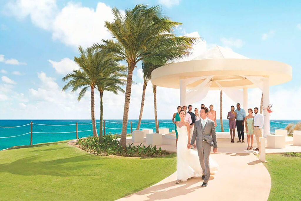 A couple walking away from having just gotten married under a tropical gazebo