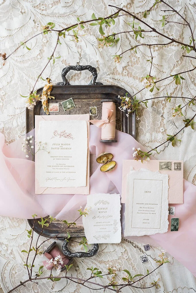 An wedding invitation, a spool of wool and other delicate details on a tray