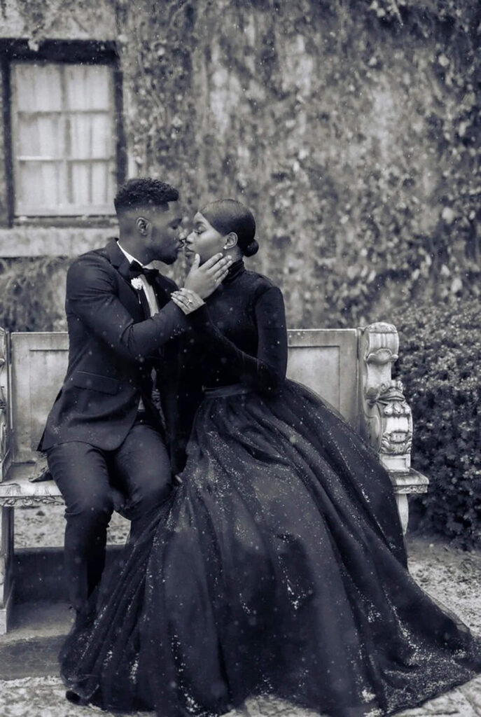 A couple dressed all in black embracing on a bench