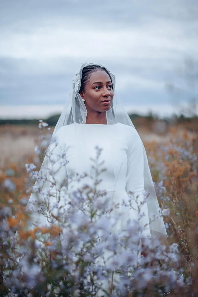 A bride with a white dress and veil in a field