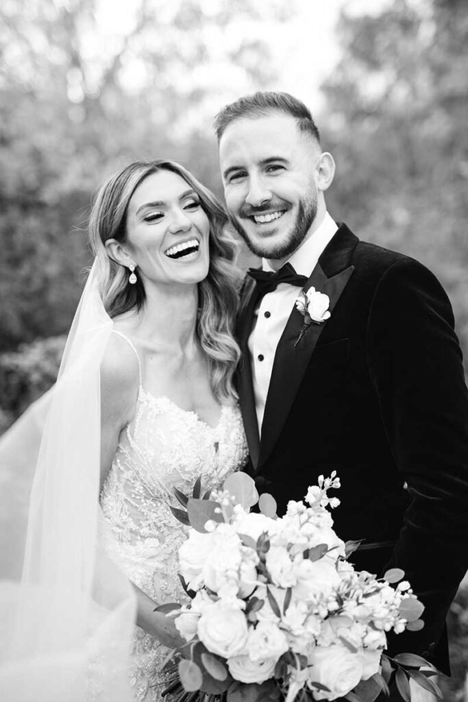 A black and white image of a couple and the bride is laughing