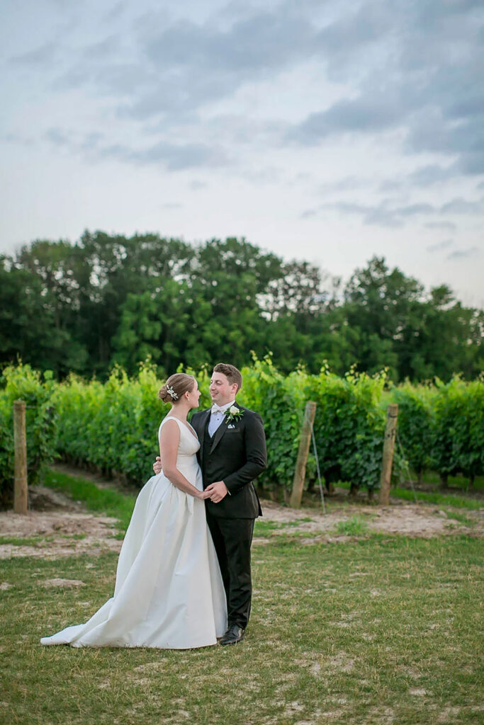 A couple walking holding hands in a vineyard