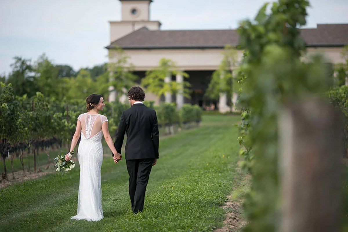 A couple walking through the vineyards at Two Sisters Winery