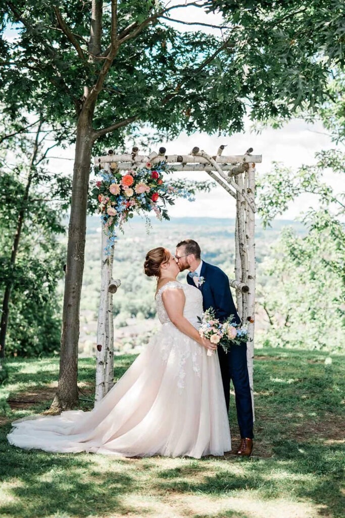 A couple kissing in from of their arbor