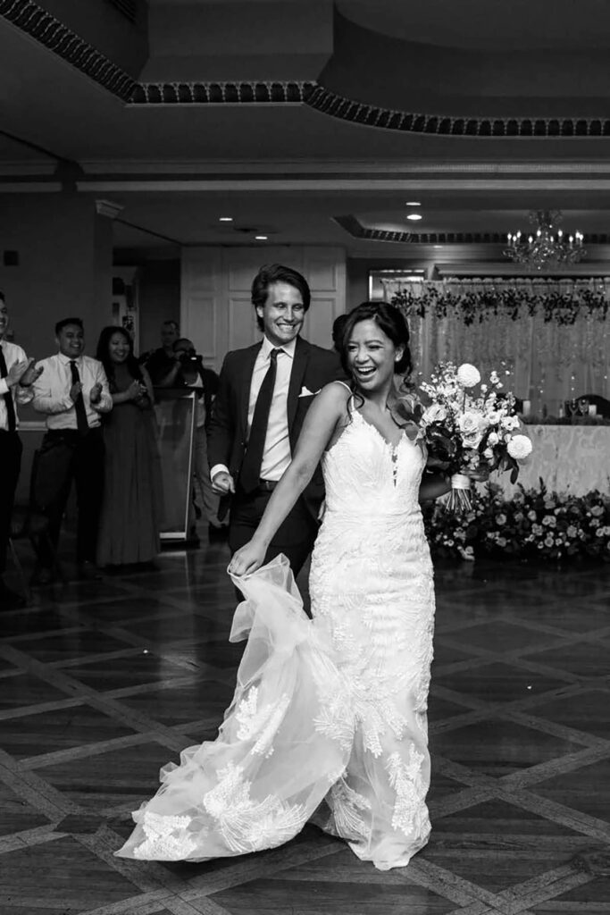 A black and white image of a couple walking into a reception hall