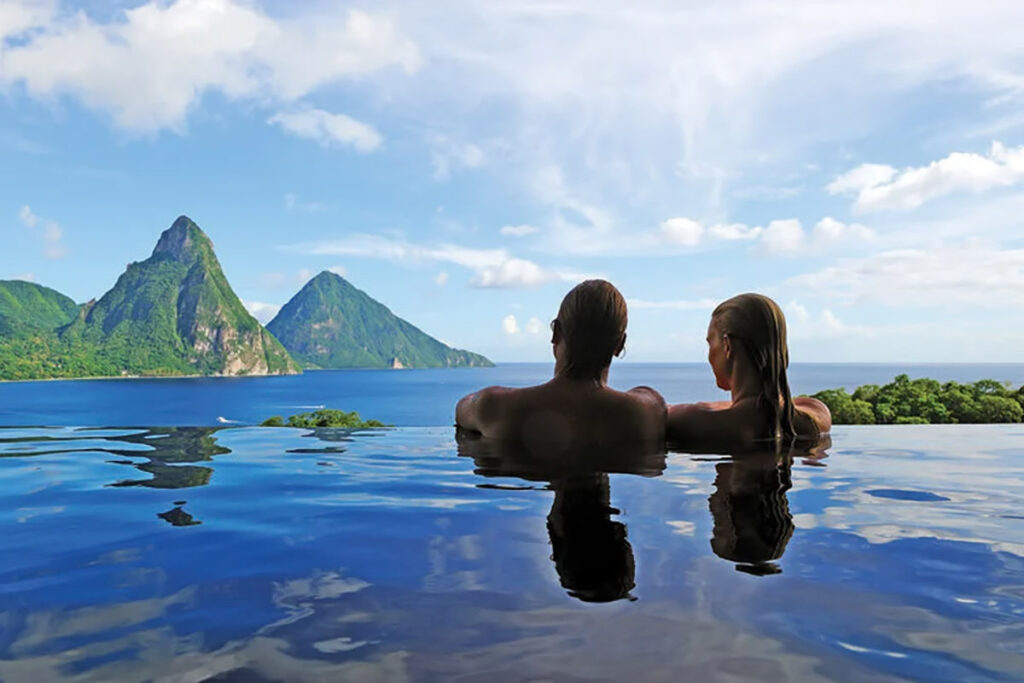 A couple looking out from an infinity pool at mountains in the distance
