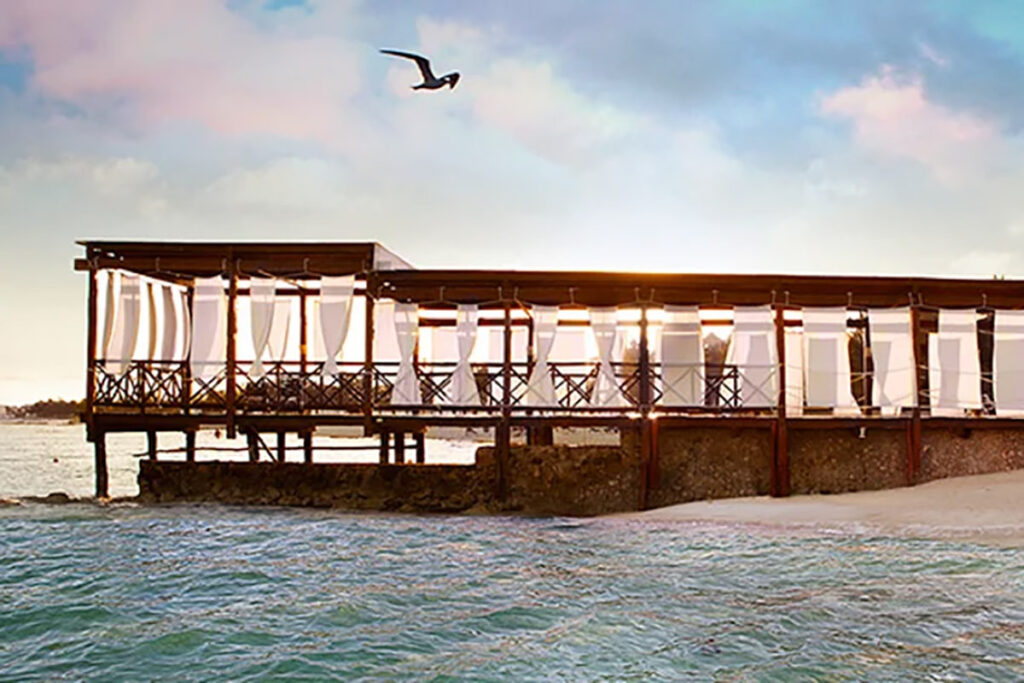 A resturant in the distance where a wedding recrption will take place beside the sand and over the water