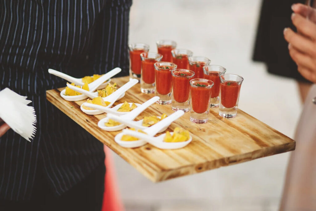 A server holding a cutting board full of appetizers