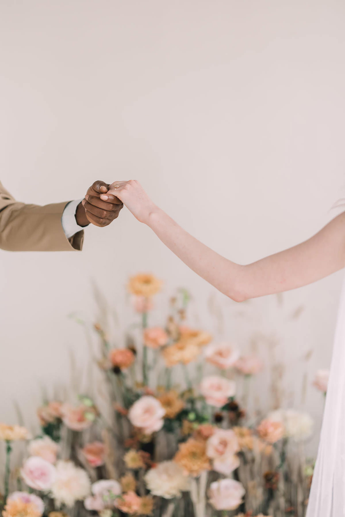 two hands holding with flowers in the background