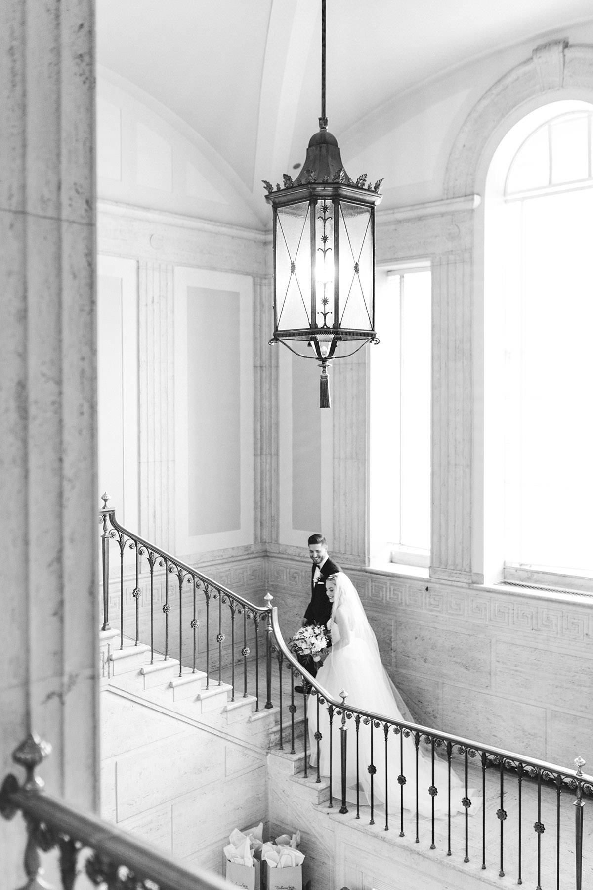 A black and white image of a couple walking up a grand staircase