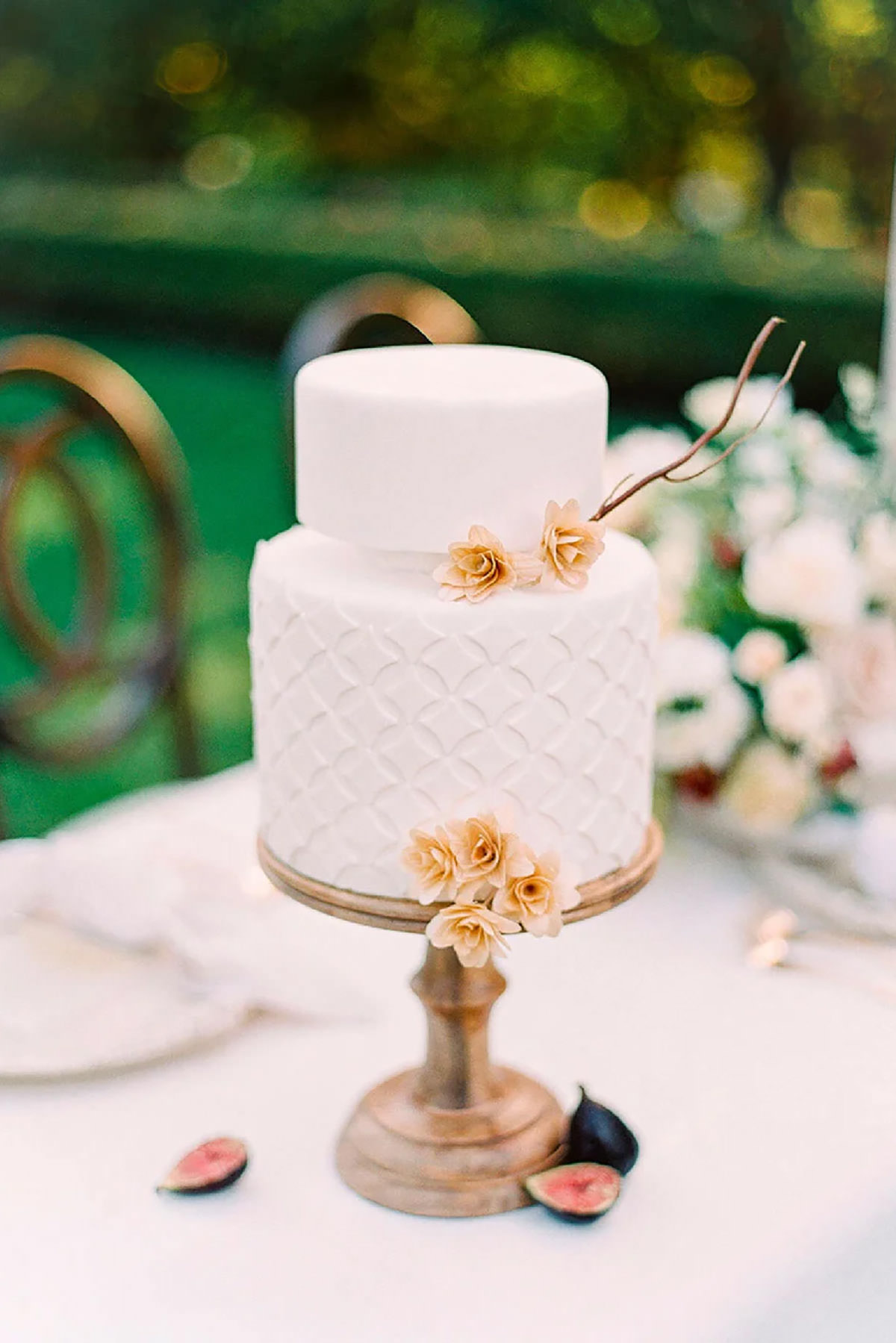 A tall white cake with flowers on it, on a table