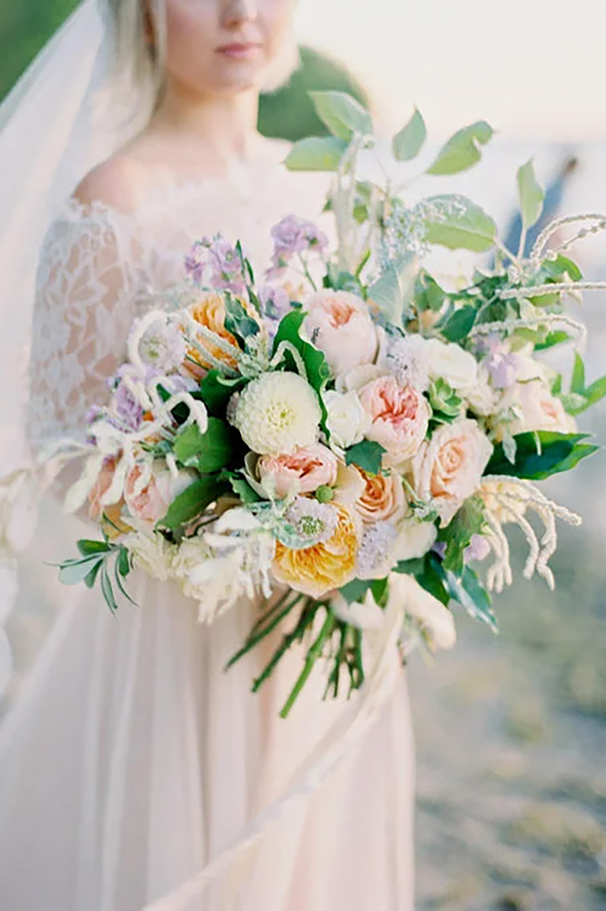 A close up of flowers being held by a bride on a beach