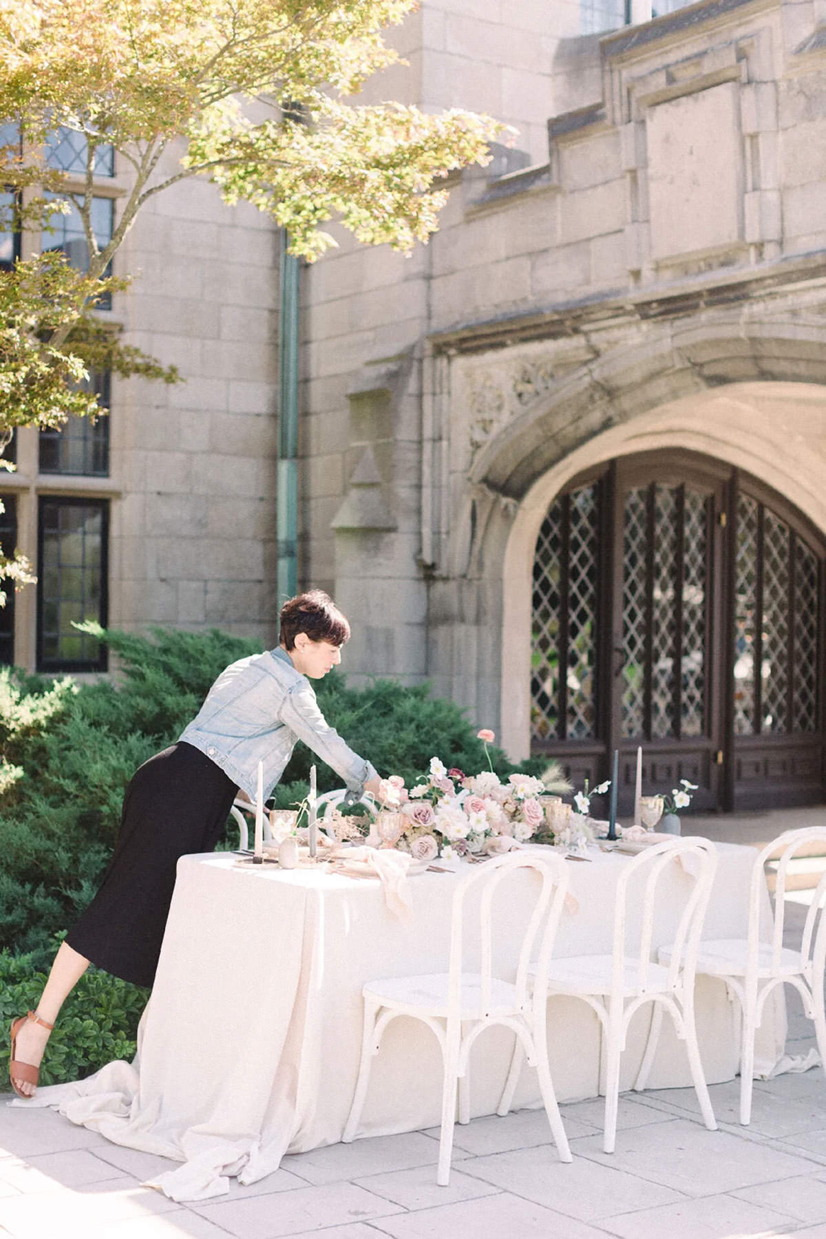 A girl attending to details of a wedding table in front of a historical building