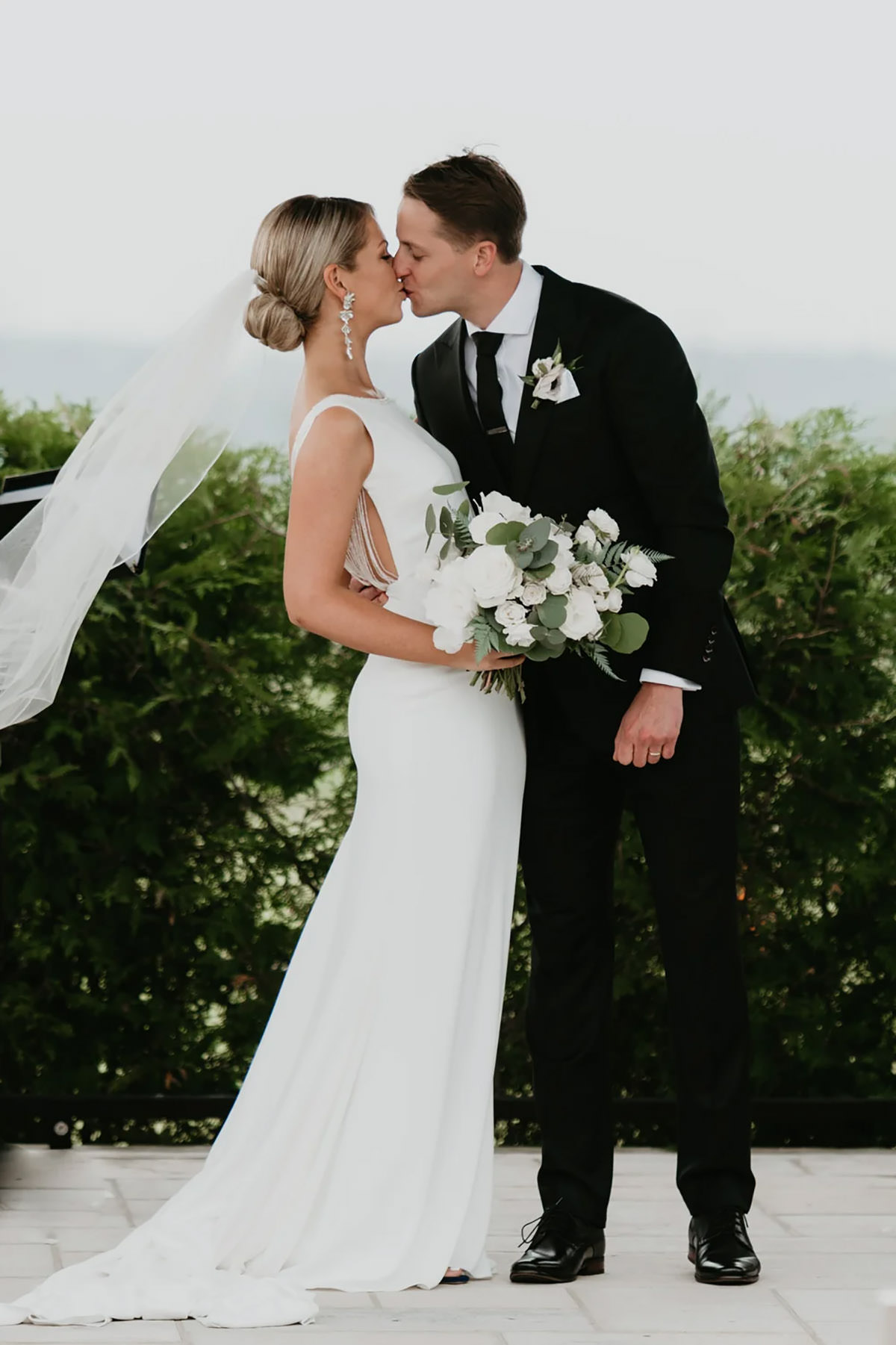 Bride and groom sharing a kiss with a blowing veil