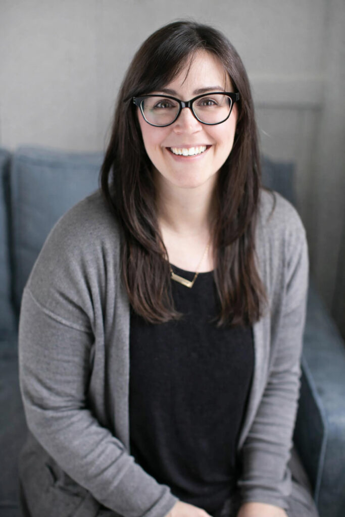 A headshot of a girl with black framed glasses and long brown hair