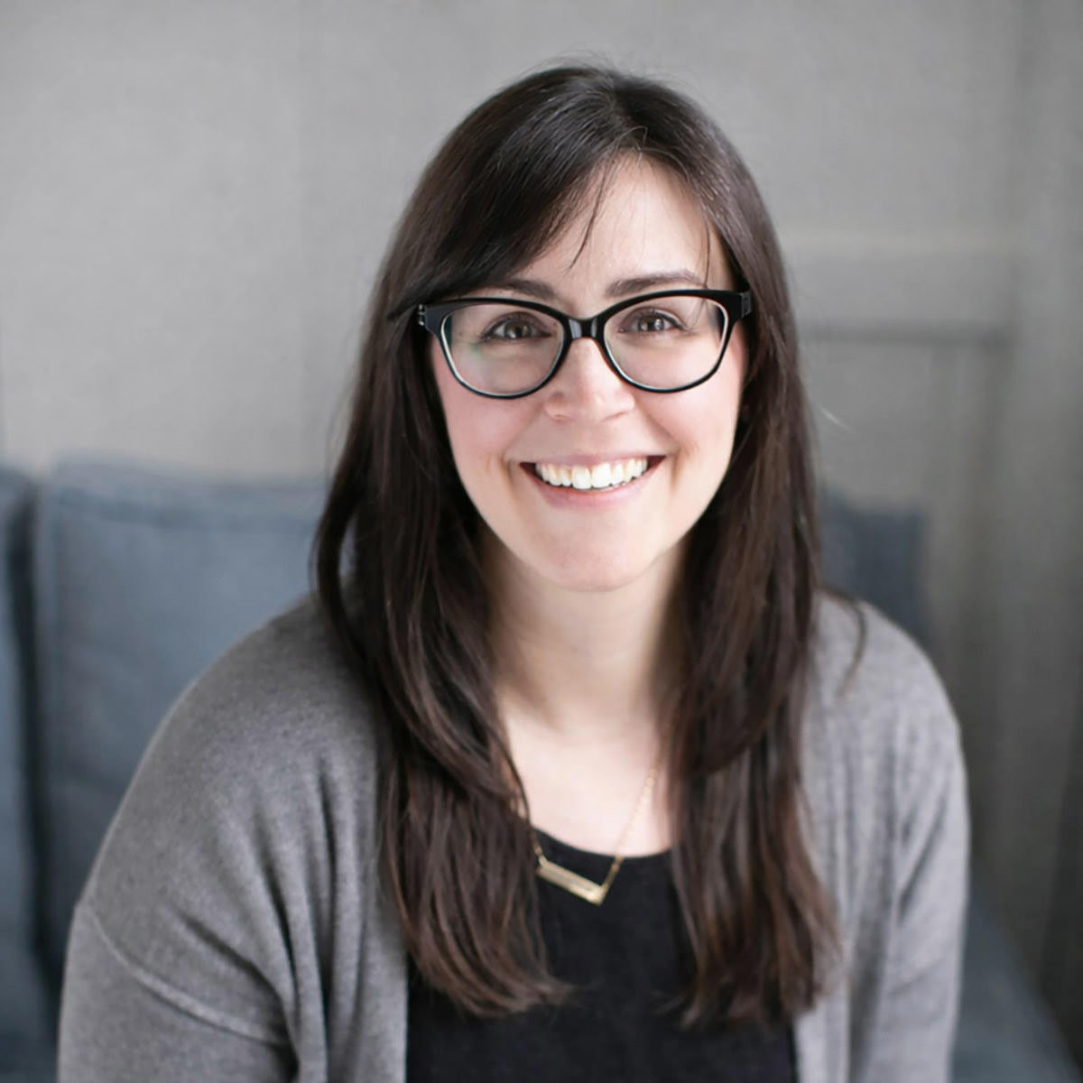 A headshot of a girl with black framed glasses and long brown hair