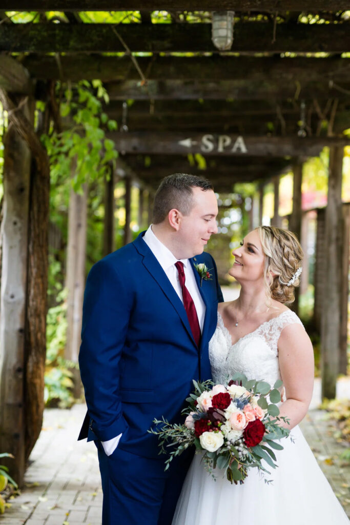 A couple looking at each other under a long wooden pergola