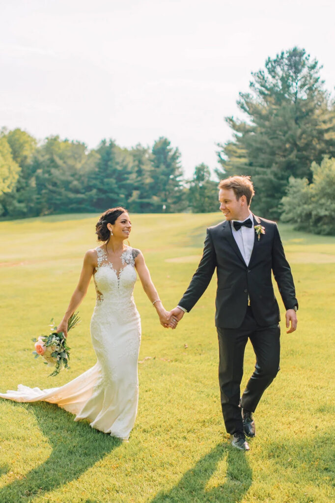 A couple walking in an open field hand in hand on their wedding day