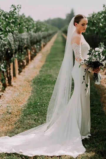A bride in a lush vineyard look at her flowers