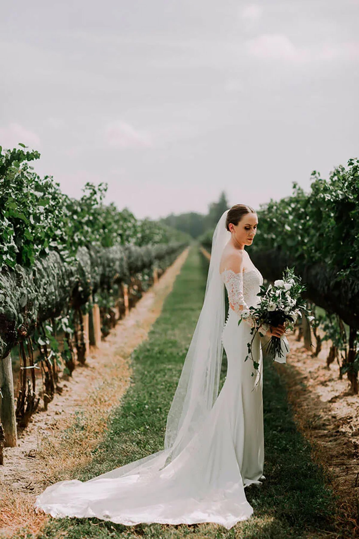 A bride in a lush vineyard look at her flowers