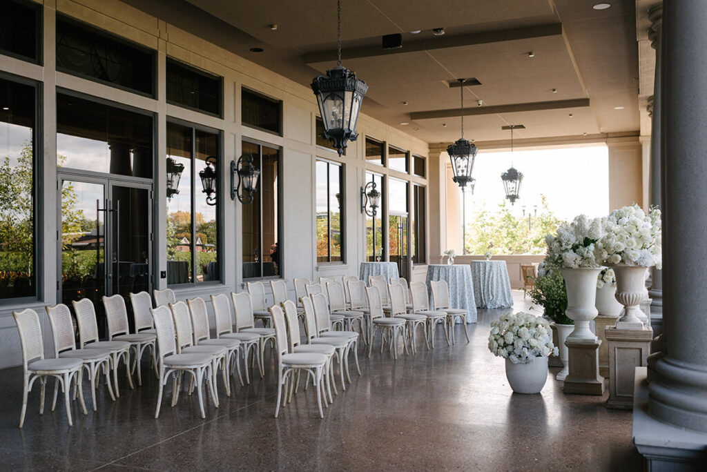 A ceremony setup on a large porch with large lanterns above and lots of white flowers