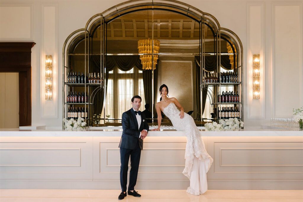 A couple sitting and leaning on a long bar top in an elegant ballroom