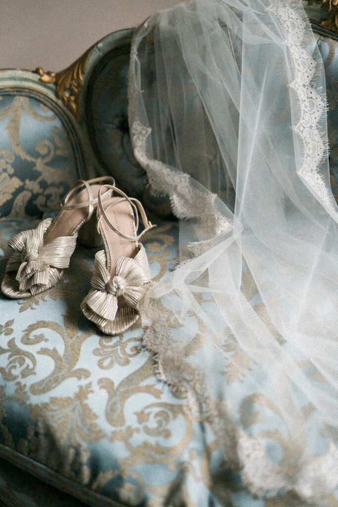 A pair of shoes and veil on a blue chair.