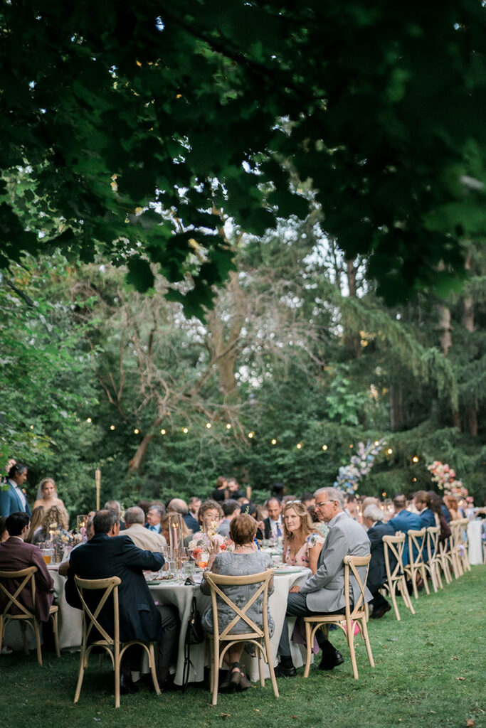 A pulled back image of a wedding reception and guests seating at outdoor tables.