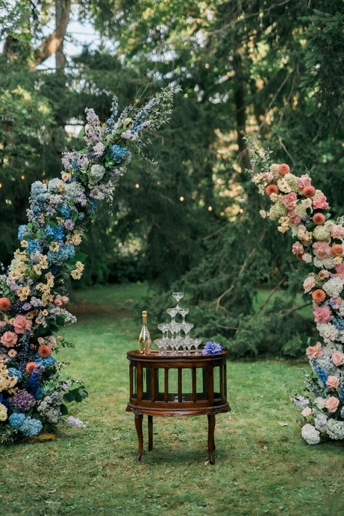 A champagne tower under a floral arch.