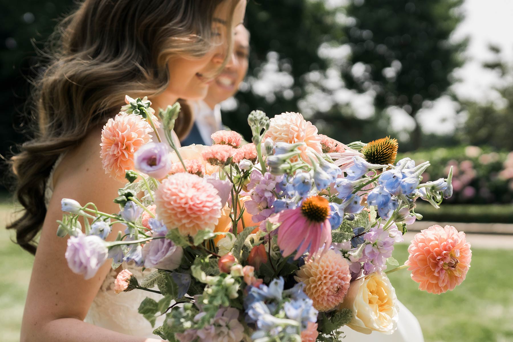 bride carrying a colourful bouquet of summer flowers