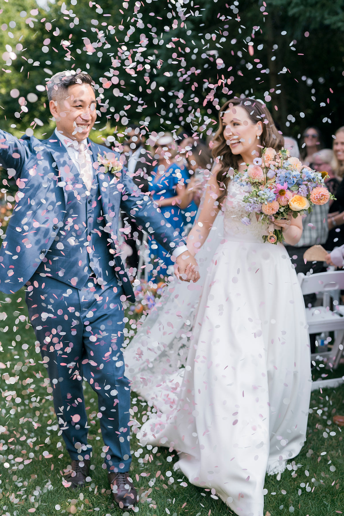 bride and groom being showered with pink confetti