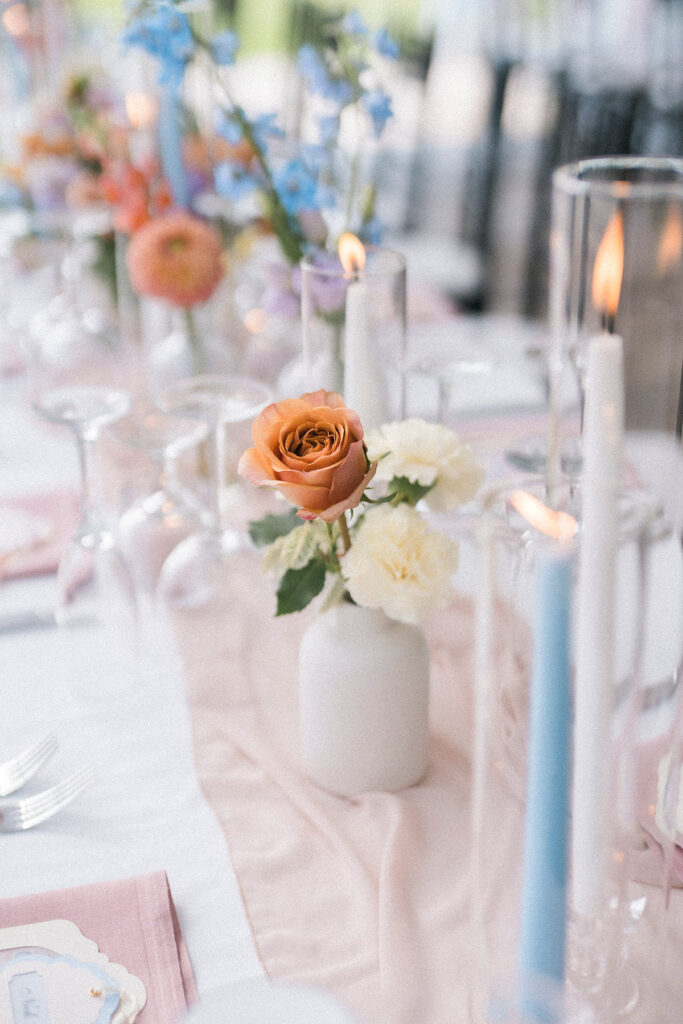 wedding tablescape with bud vases, pink runner, and blue taper candles