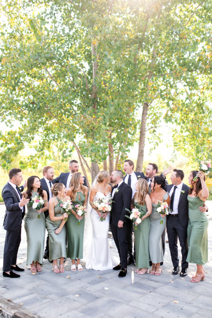 A couple kissing and the wedding party cheering around.
