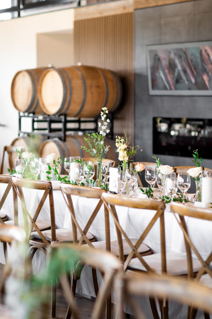 A bright reception room with white tablecloths and green flowers.