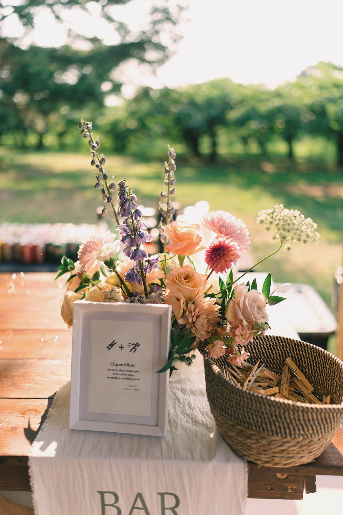Flowers on a table at a wedding reception outside with orchards in the back