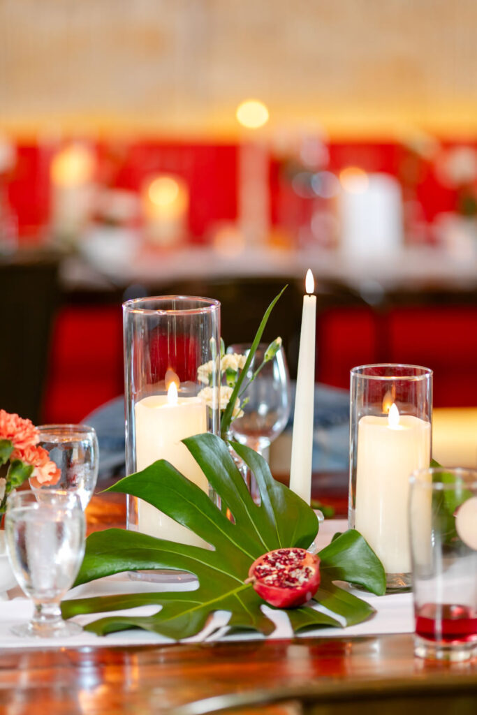 Reception table decor of a tropical leaf and pomegranate beside candles