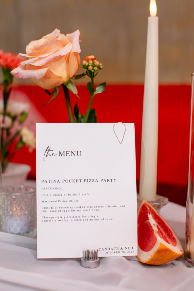 A close up of a wedding menu on a table with candles and flowers