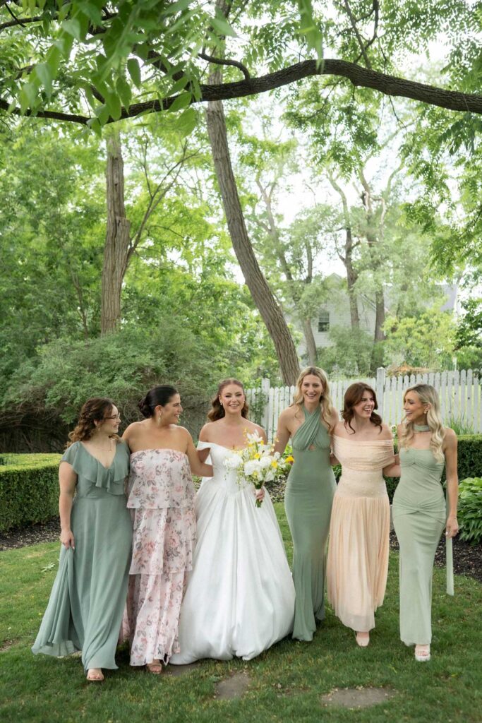 bride walking with bridesmaids in mismatched green dresses