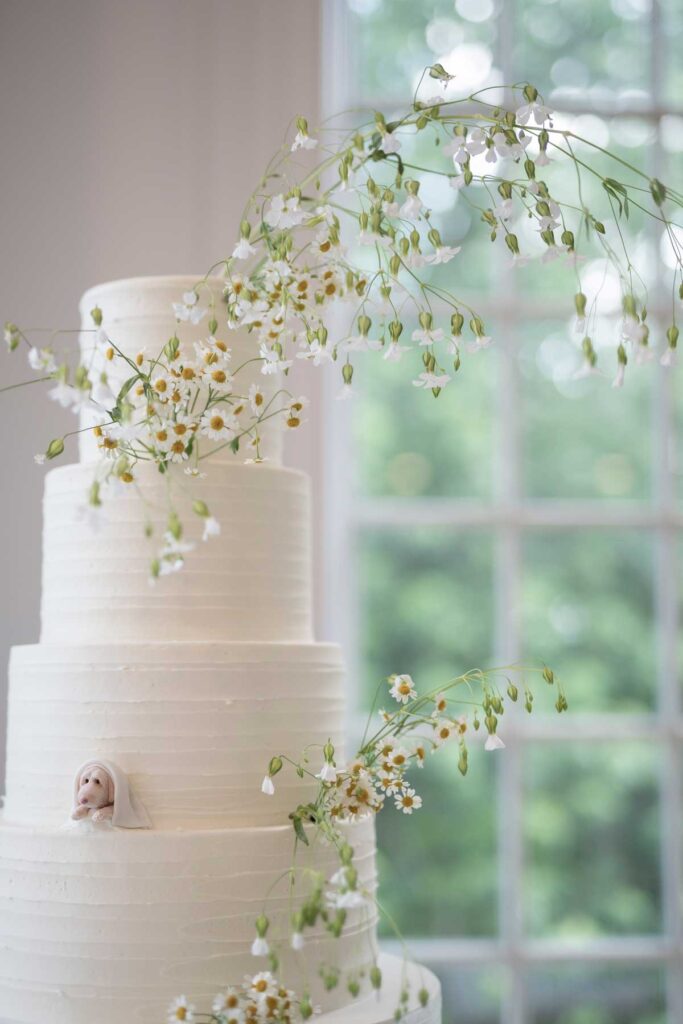 white multi-tier wedding cake with baby's breath and small fondant dog
