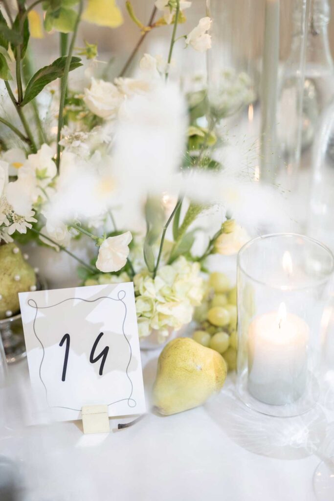 wedding reception centrepiece with table number and floral arrangement including fruit