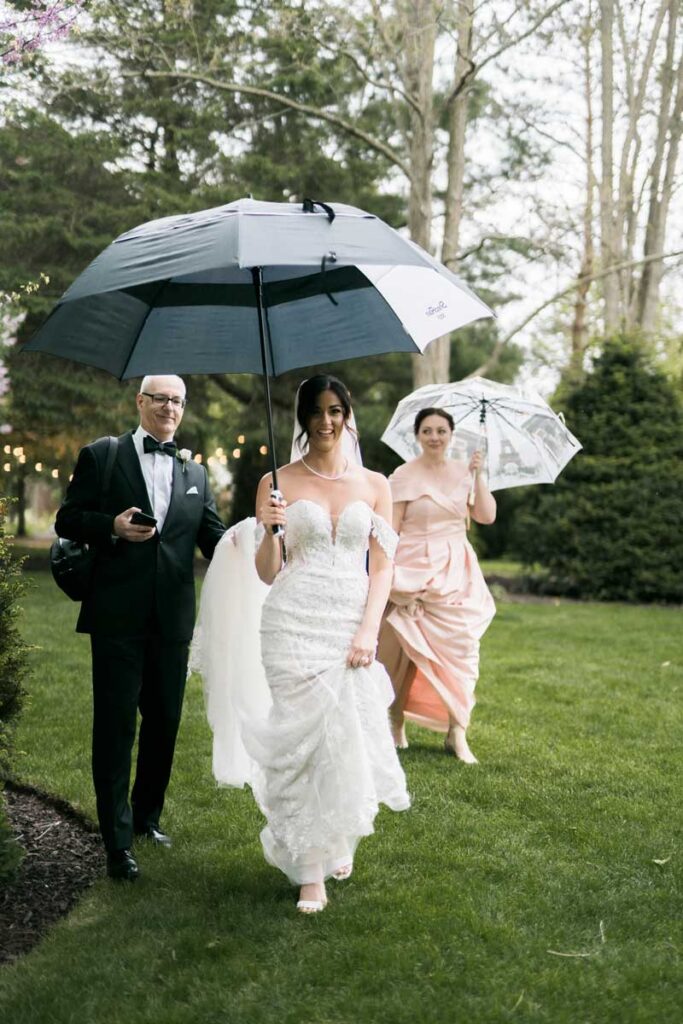 bride and wedding party walking under umbrellas