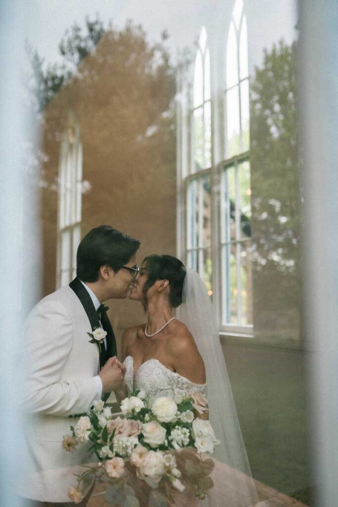 bride and groom seen through a chapel window